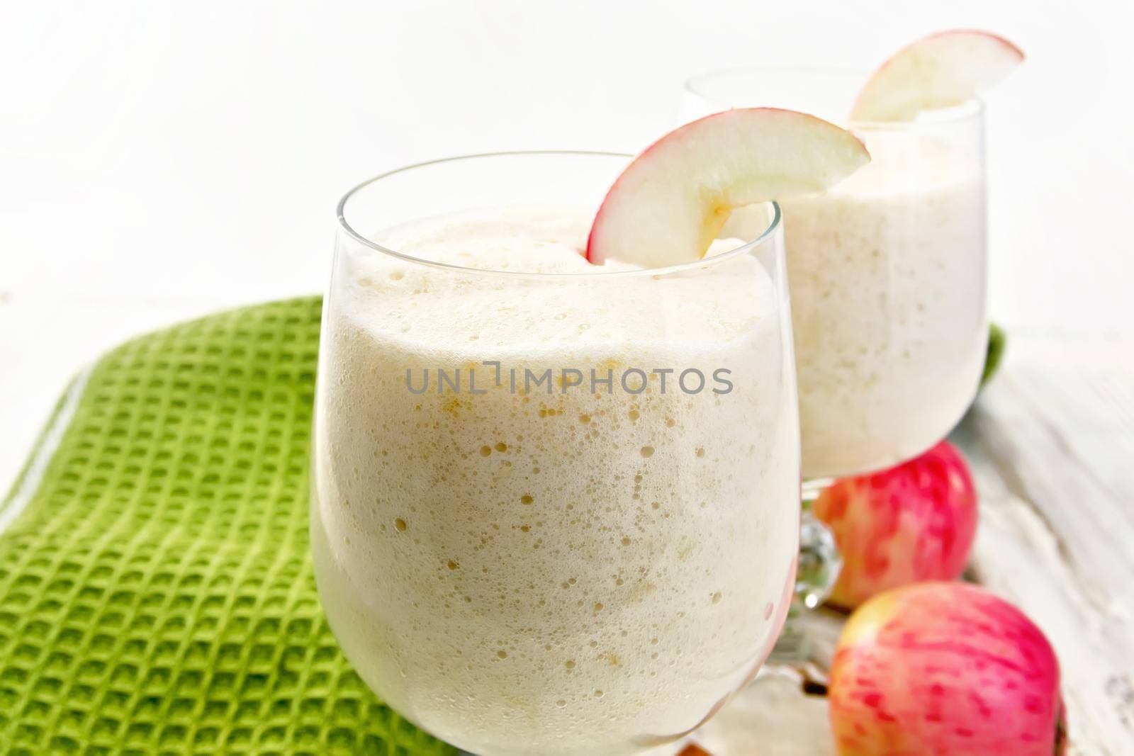 Air apple jelly in glass glasses, red apples and a napkin on a wooden boards background