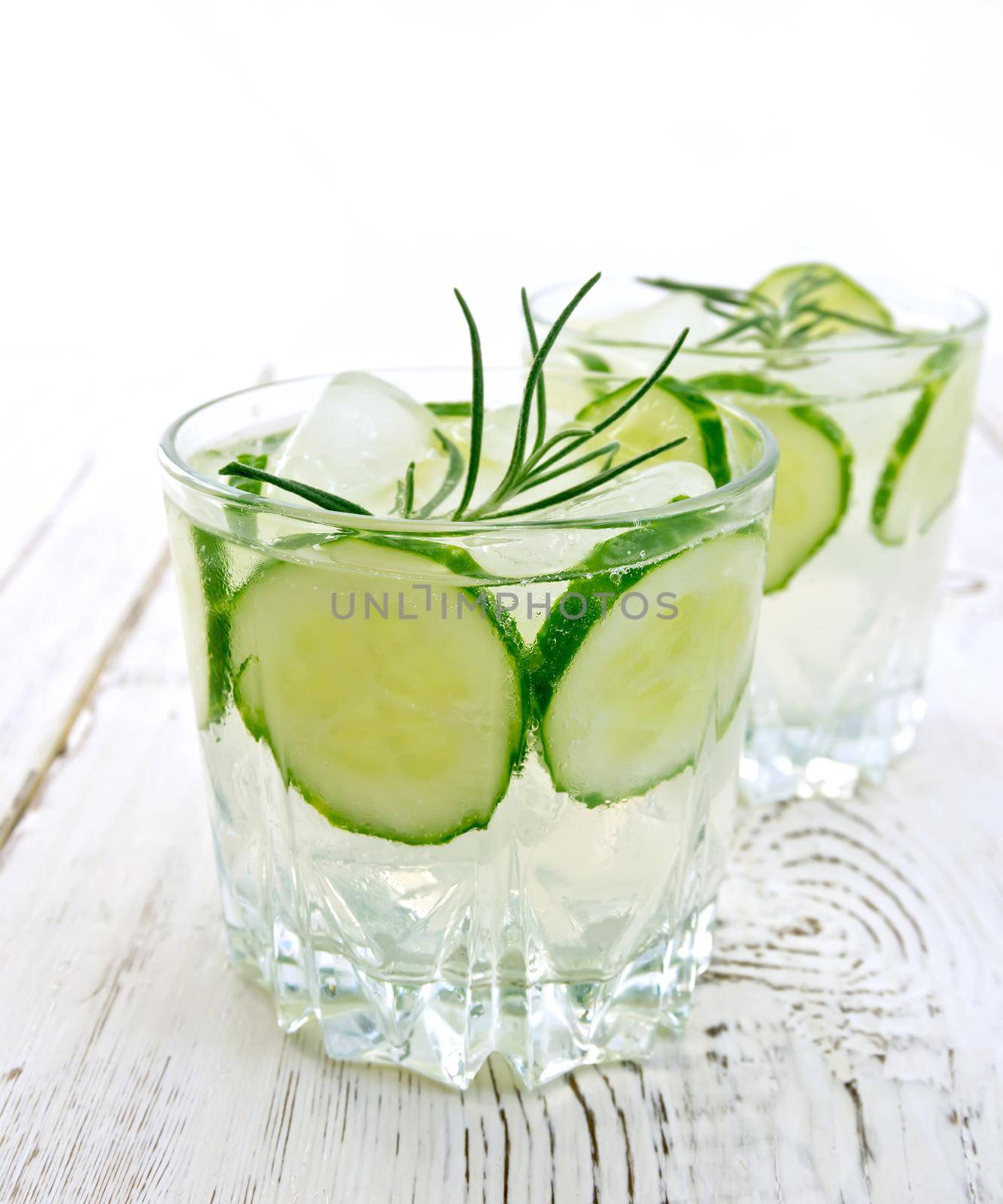 Lemonade with cucumber and rosemary in two glassful on table by rezkrr