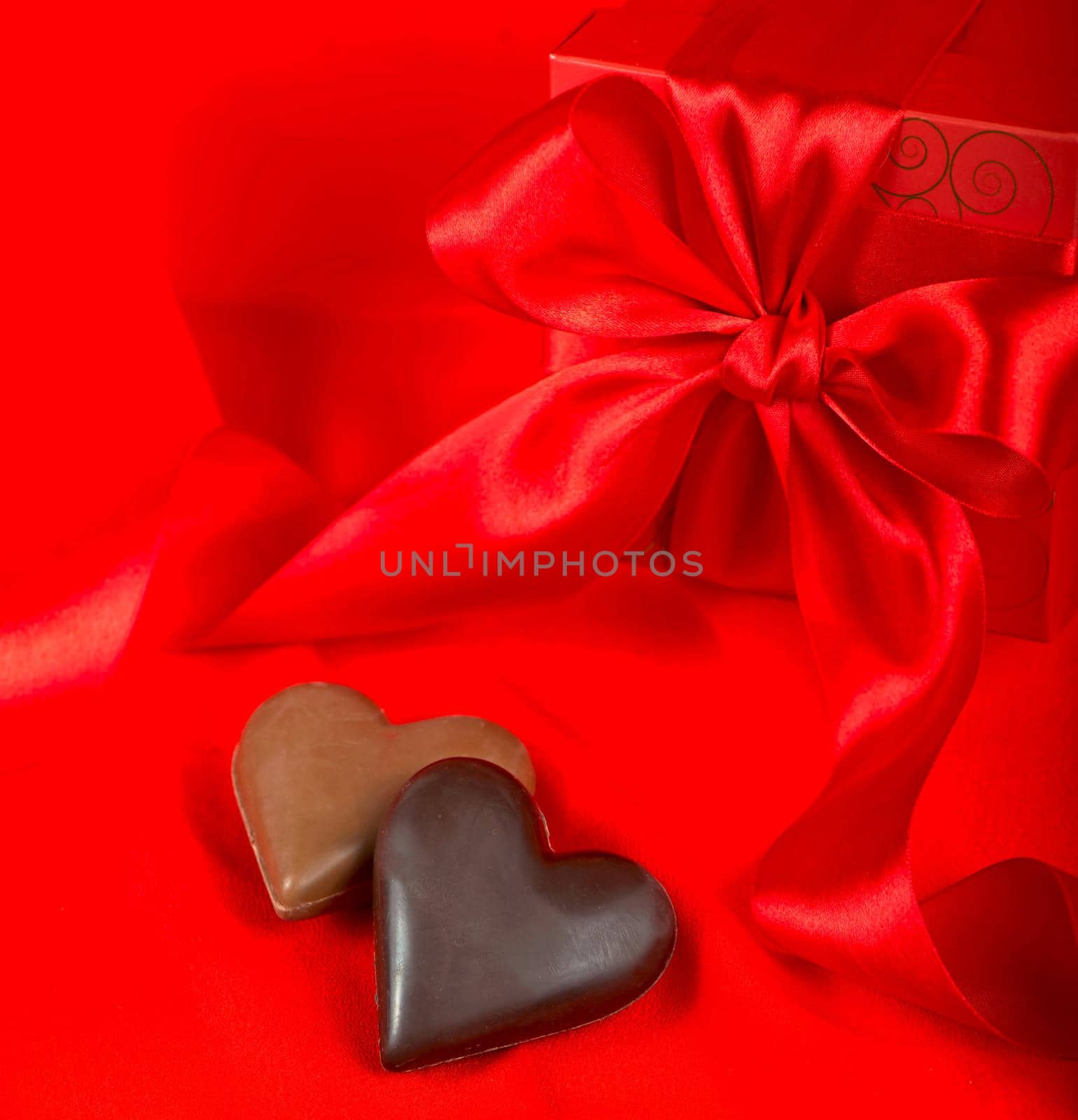 Chocolate candies in the shape of a heart on a red background. by aprilphoto