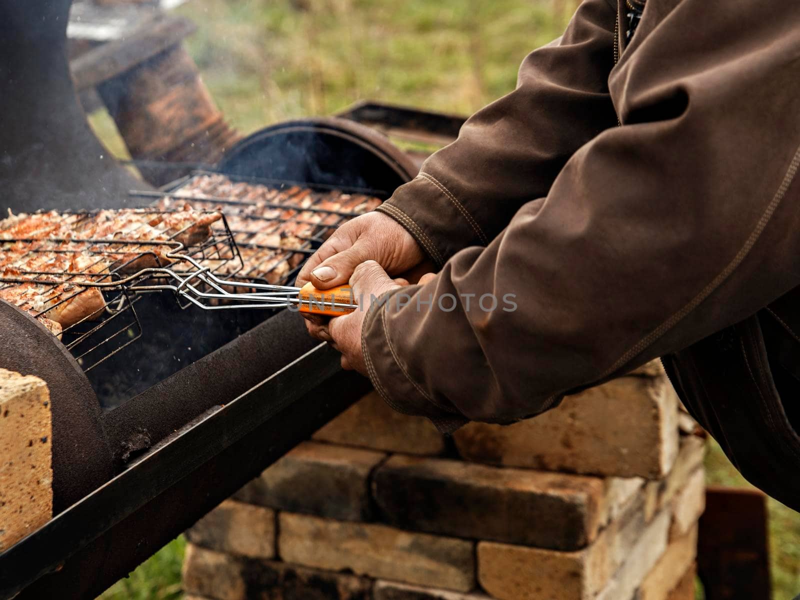 Man turns meat over for barbecue on grill.