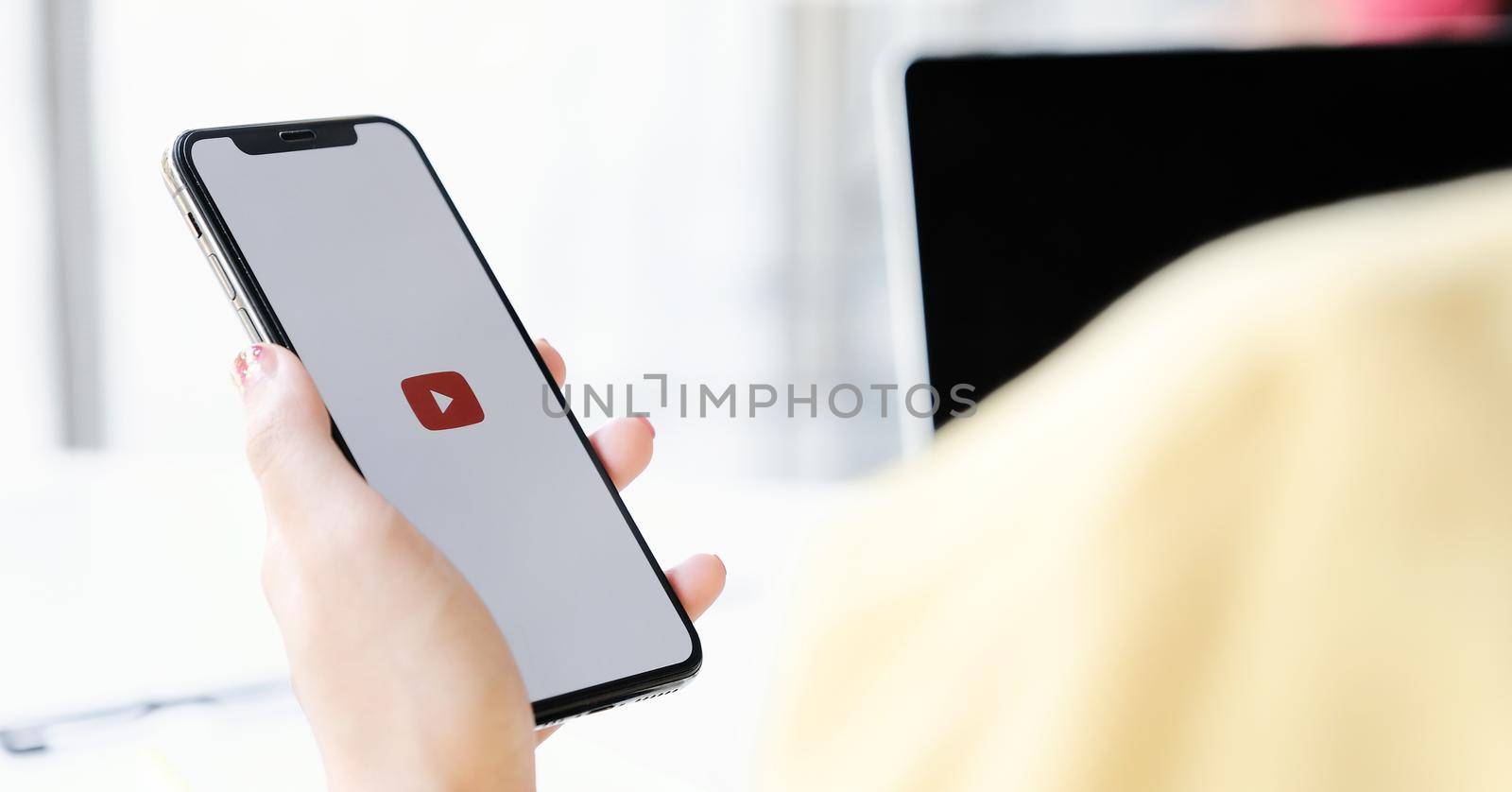 CHIANG MAI, THAILAND - MAR 7 ,2020: Woman holding iPhone Xs with Youtube apps on screen. YouTube is the popular online video sharing website. by nateemee