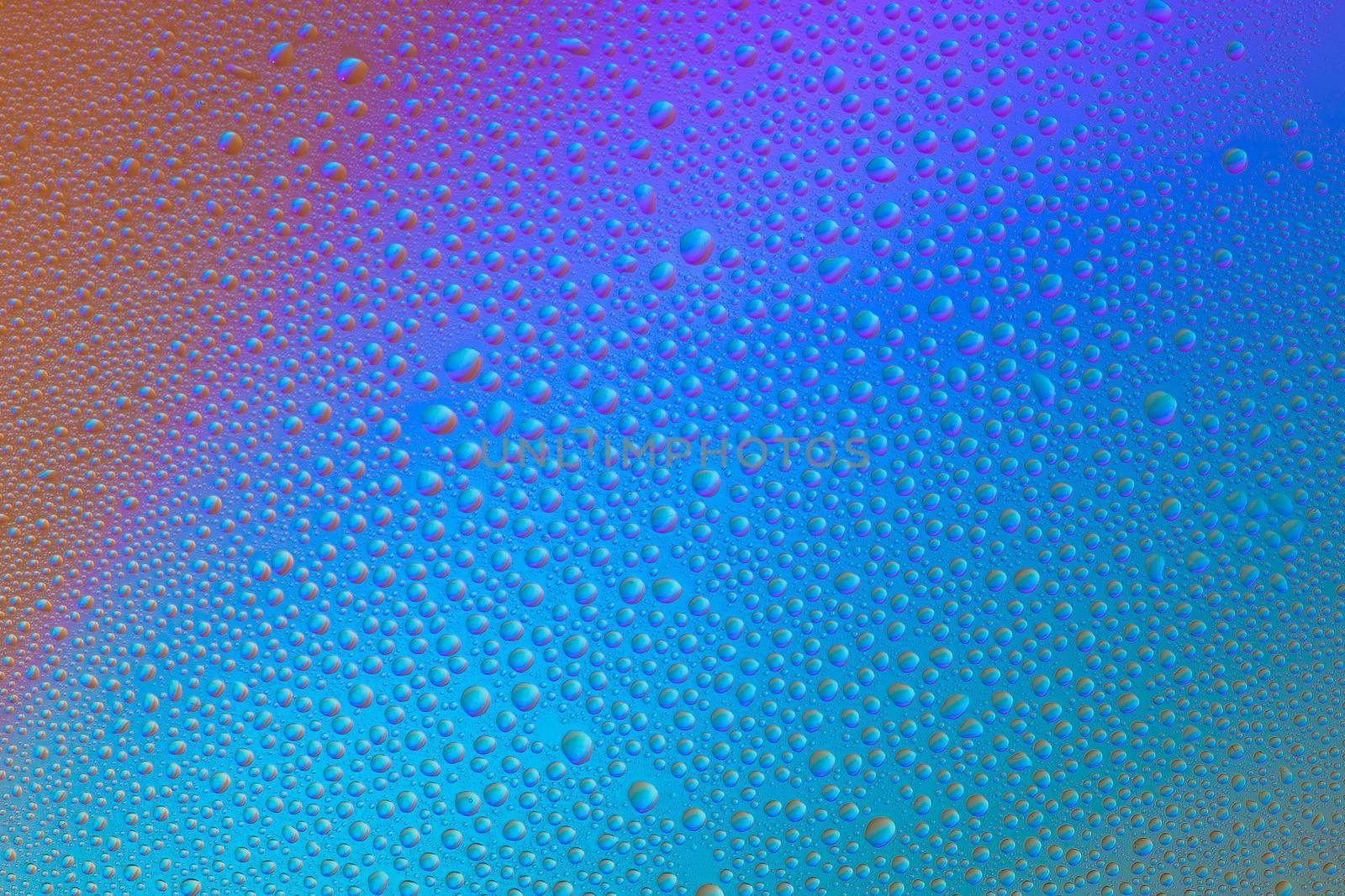 Colored abstract background from drops on glass. Rainbow color transitions.