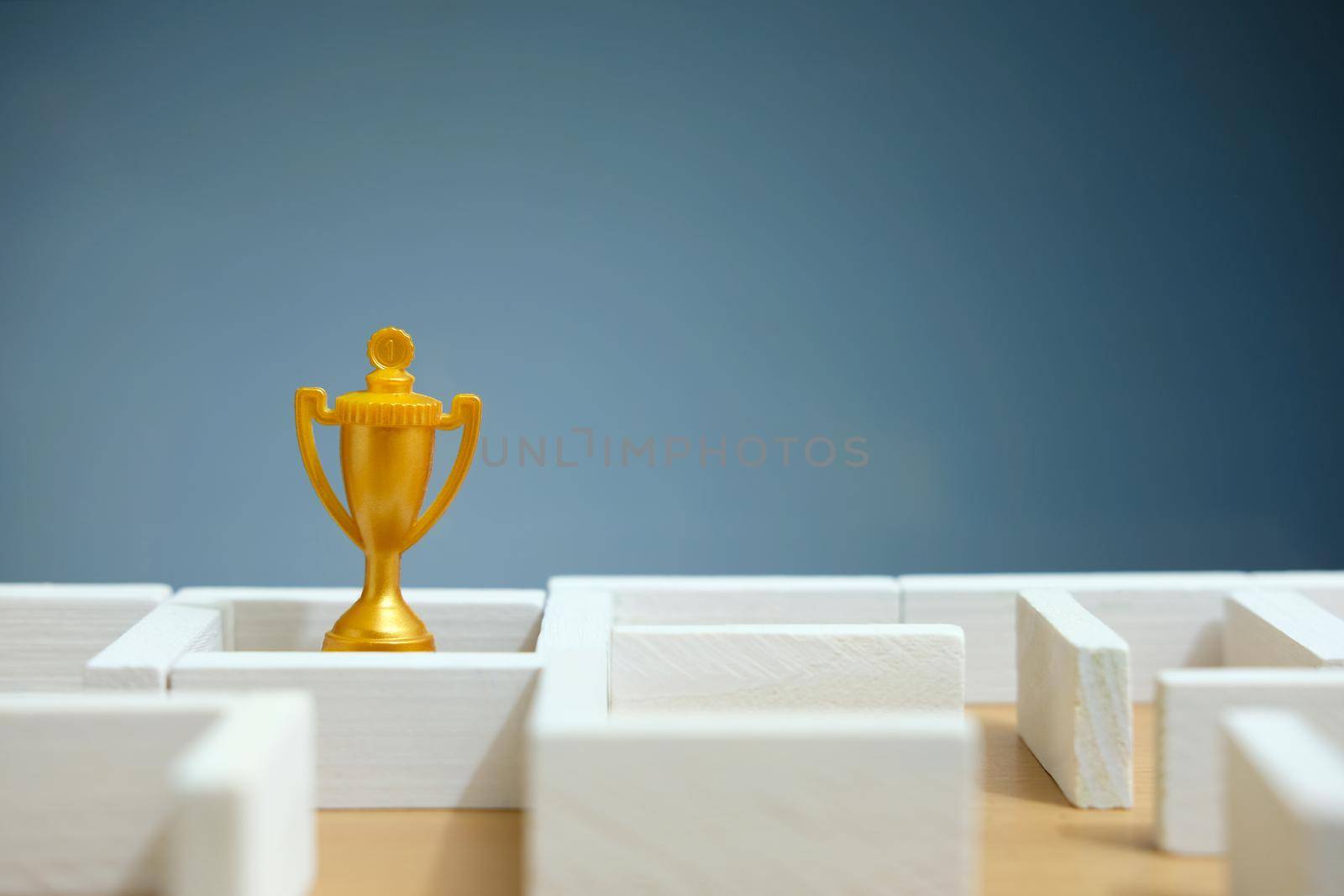 Business strategy conceptual photo - Miniature of businessman on a labyrinth maze seeking the golden trophy. Image photo