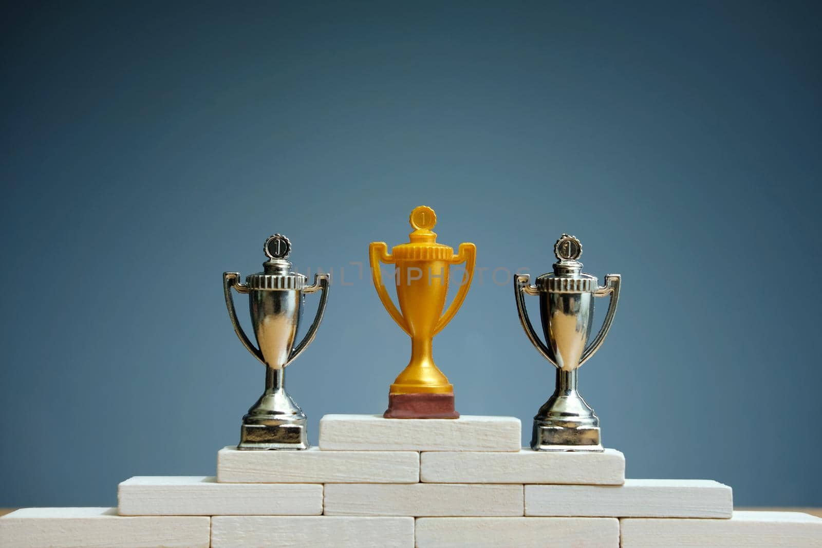 Golden and silver trophy standing on white podium. Image photo