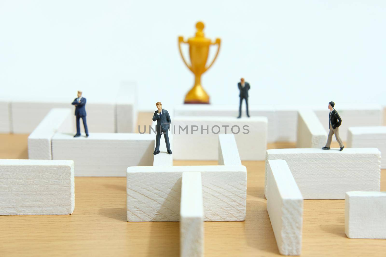 Business strategy conceptual photo - Miniature of businessman on a labyrinth maze seeking the golden trophy. Image photo