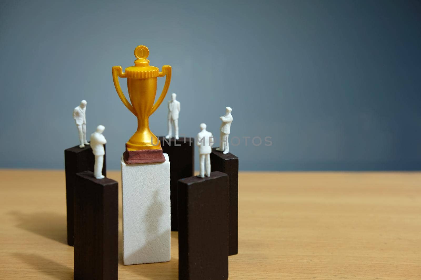 Business conceptual photo – group miniature of businessman have a group discussion above wooden puzzle block to reach golden trophy. Image photo