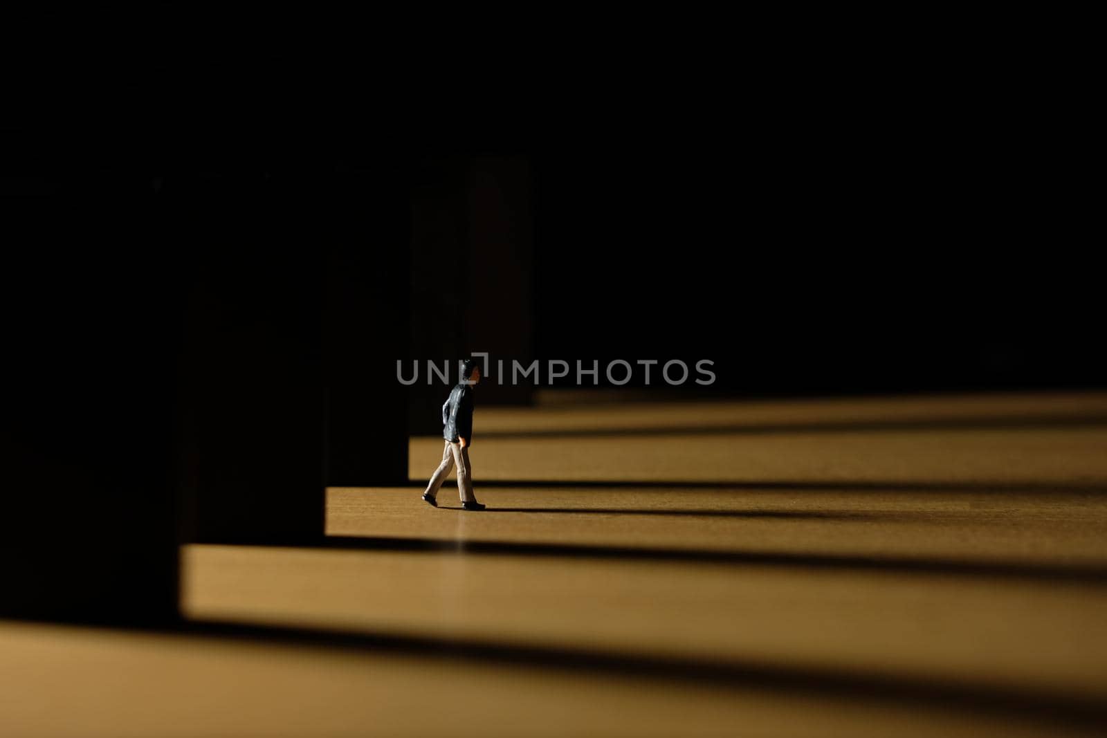 Business conceptual photo – miniature of businessman coming out from office building at dawn – coming home late concept. Image photo