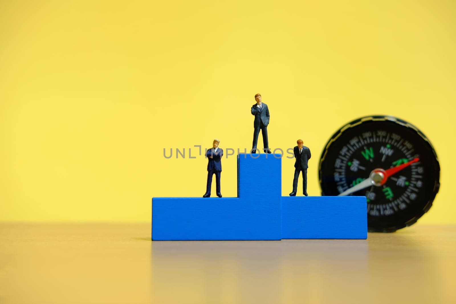 Business conceptual photo – miniature of businessman stands on wooden podium by Macrostud