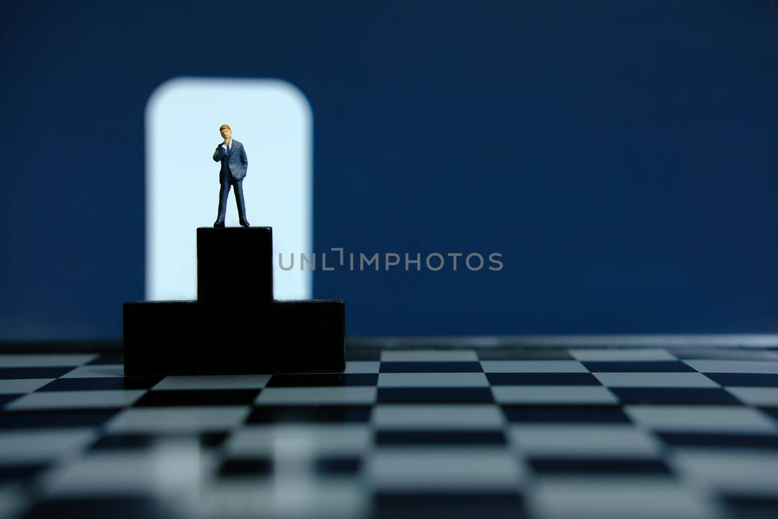 Business conceptual photo – miniature of businessman stands on wooden podium by Macrostud