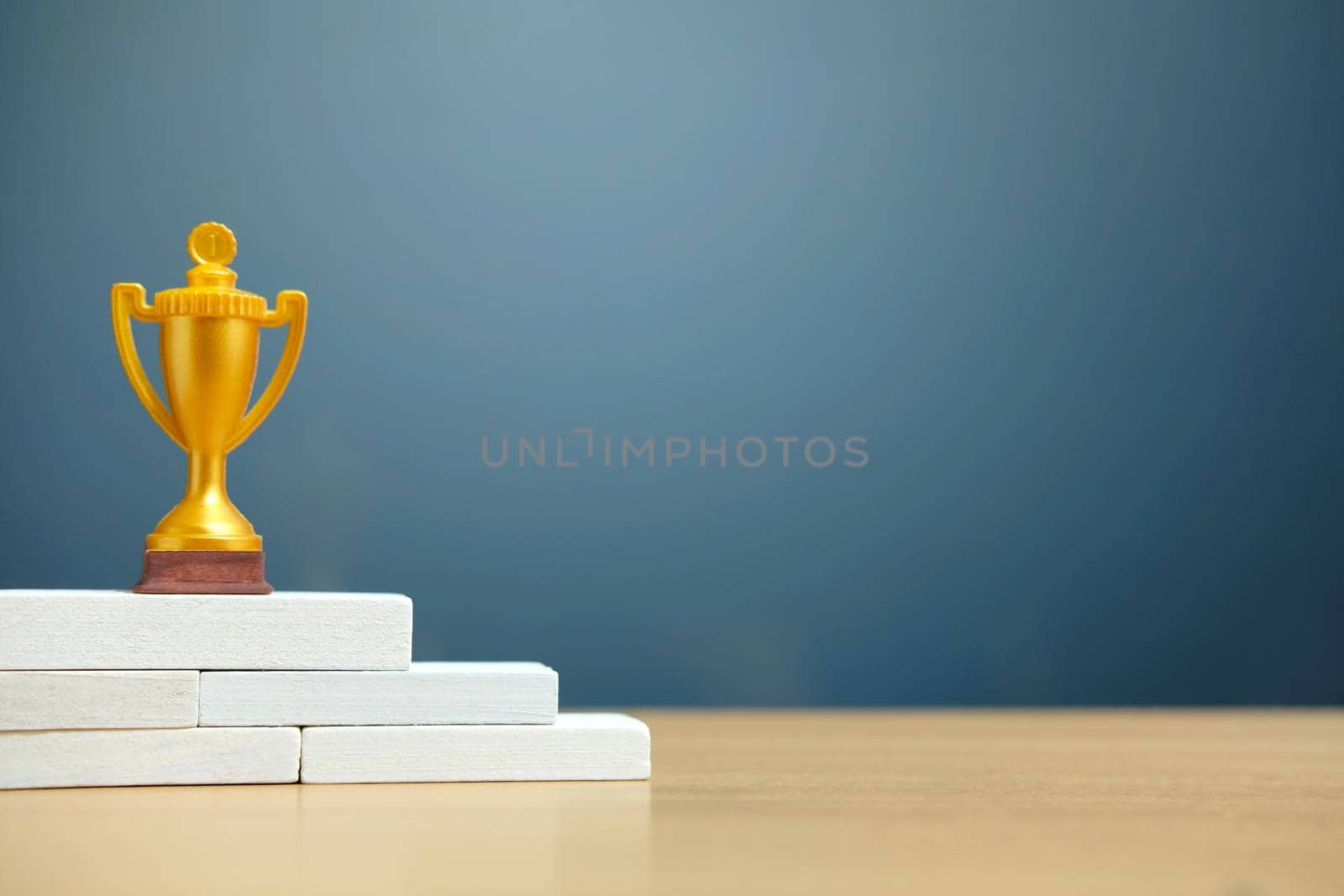 Golden trophy standing on white podium. Image photo