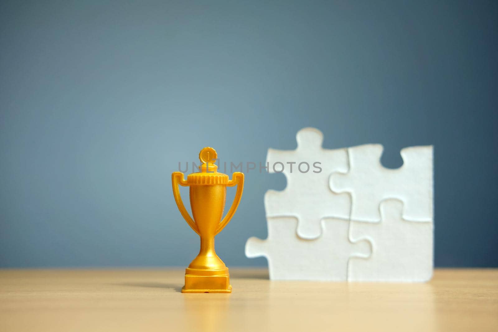 Golden trophy with white puzzle on a wooden table. Image photo
