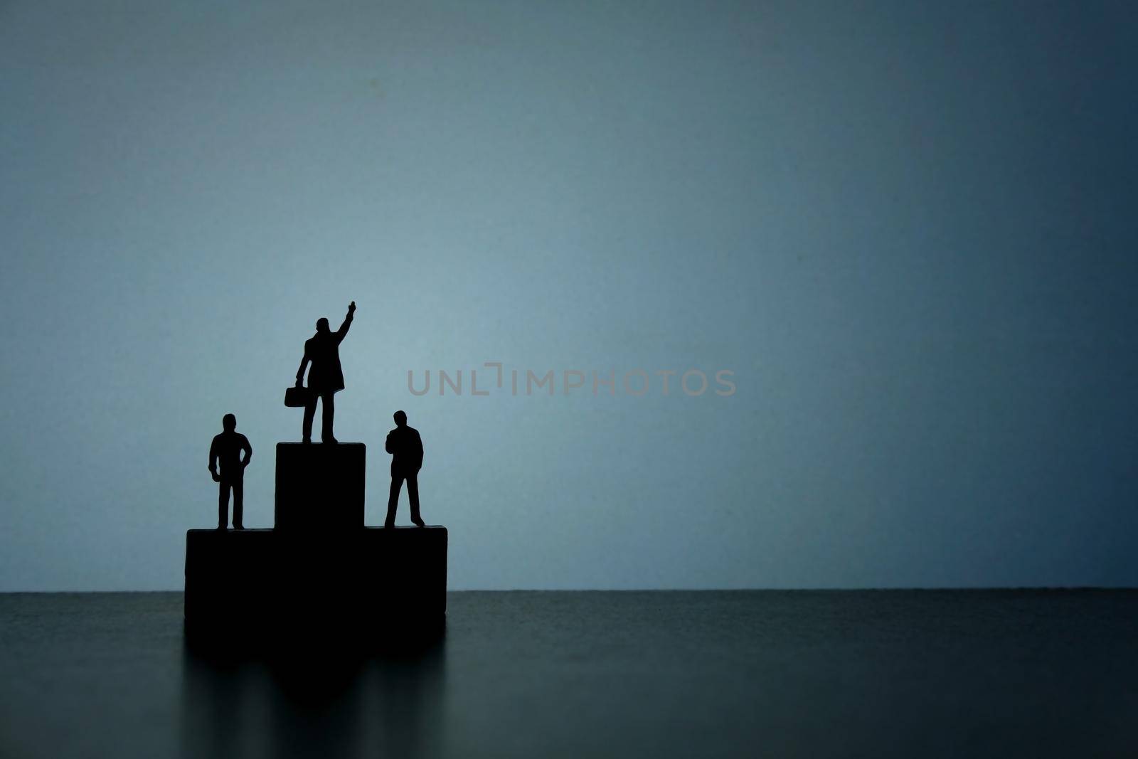 Business strategy conceptual photo - Silhouette of miniature businessman standing on podium while pointing upside. Image photo