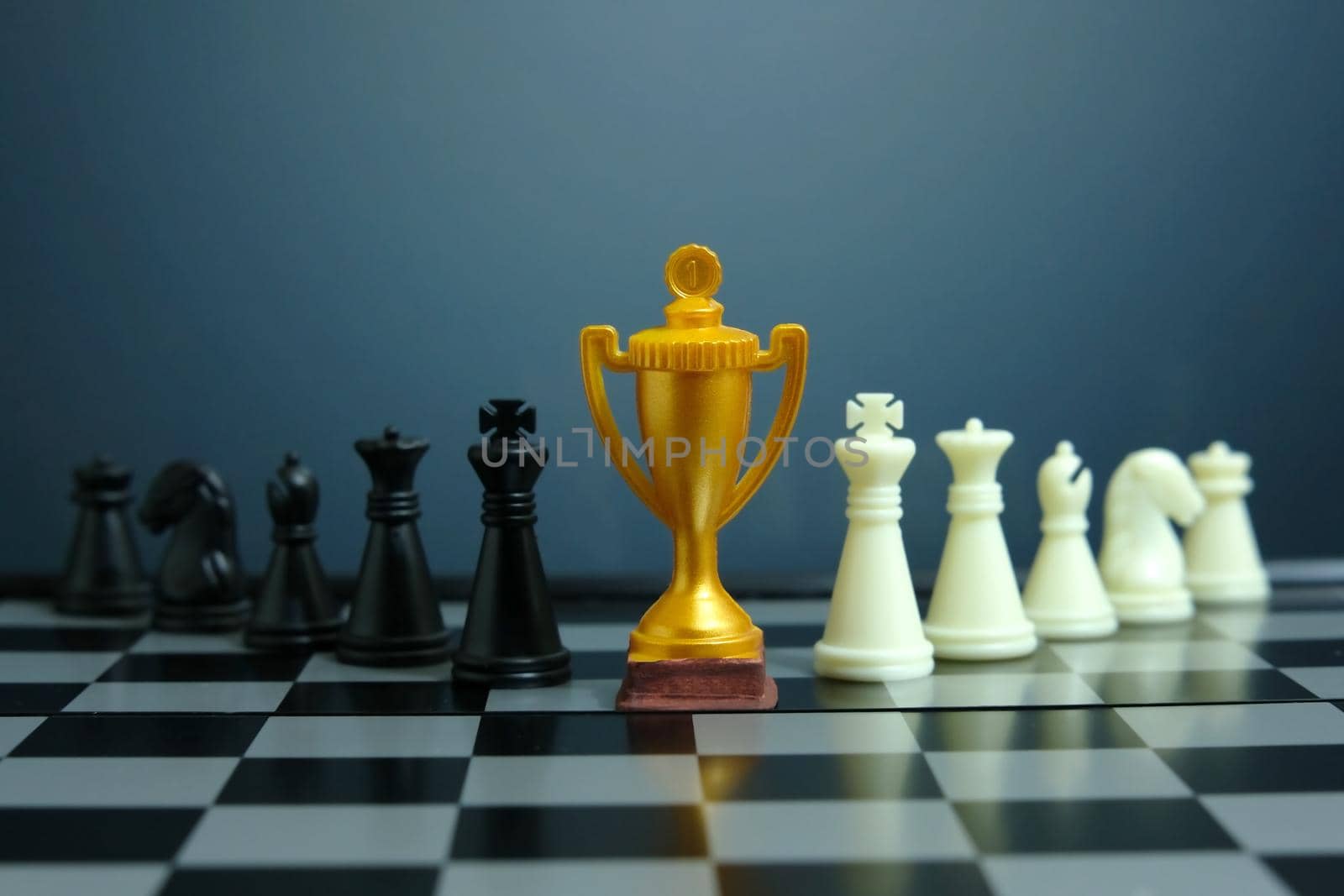 Business strategy conceptual photo – Golden trophy standing on chessboard with chess pawn. Image photo