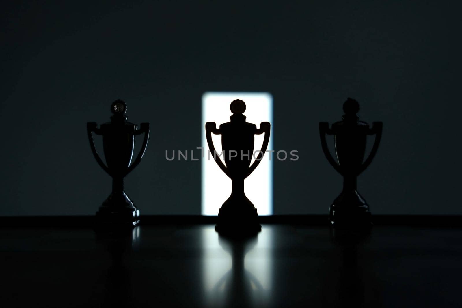 Business strategy conceptual photo – Silhouette of trophy stand in the middle of office table. Image photo