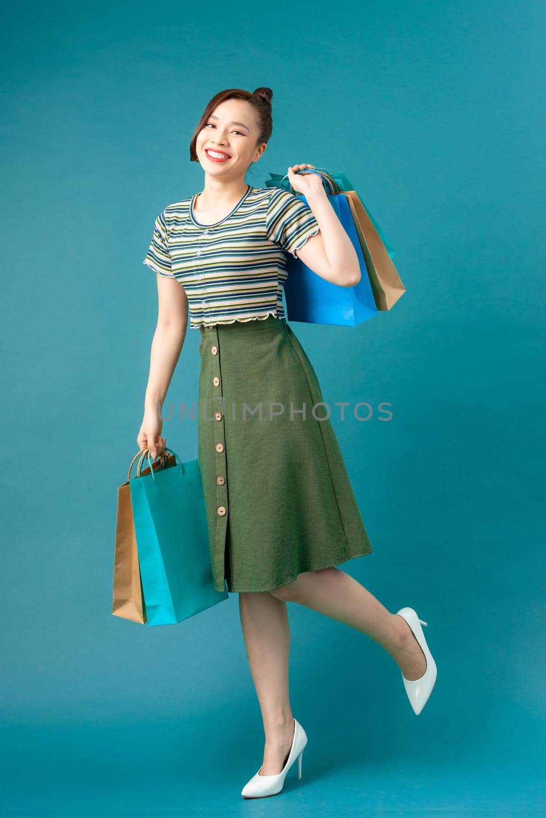 Woman wearing casual sweater on background happy enjoying shopping holding colorful bags