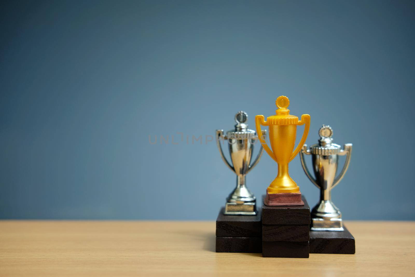 Golden trophy with two silver trophy at back stand on black podium. Image photo