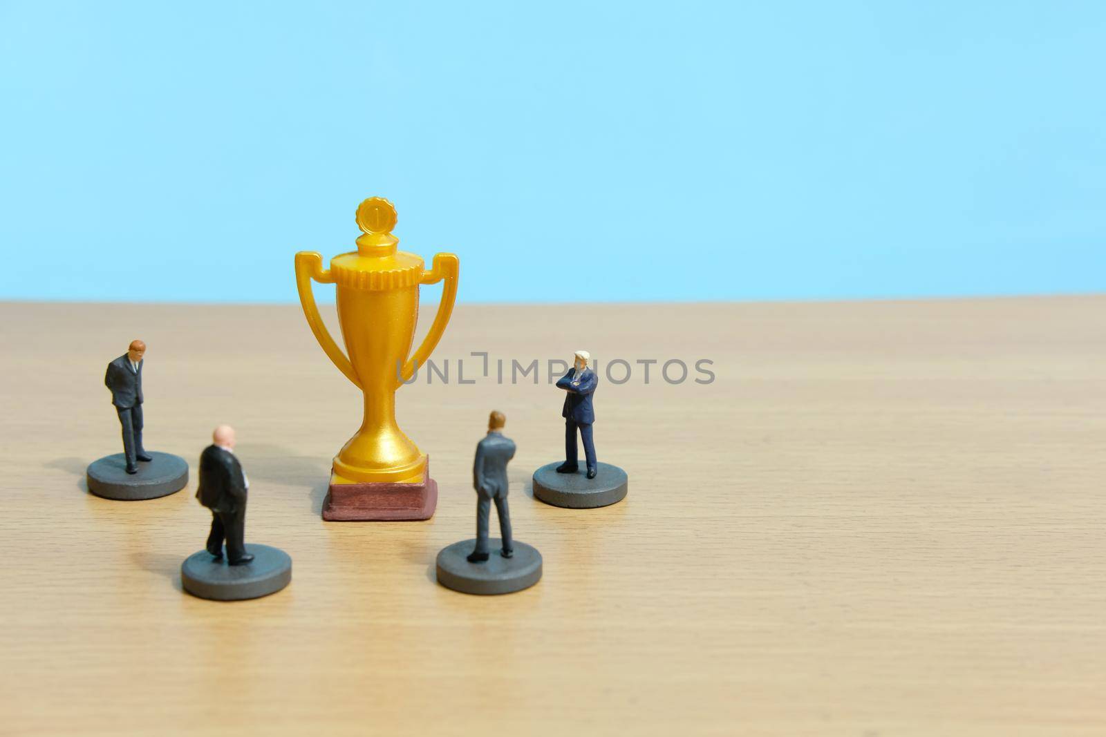 Miniature business concept - businessman lineup rank with golden trophy in the middle. Image photo