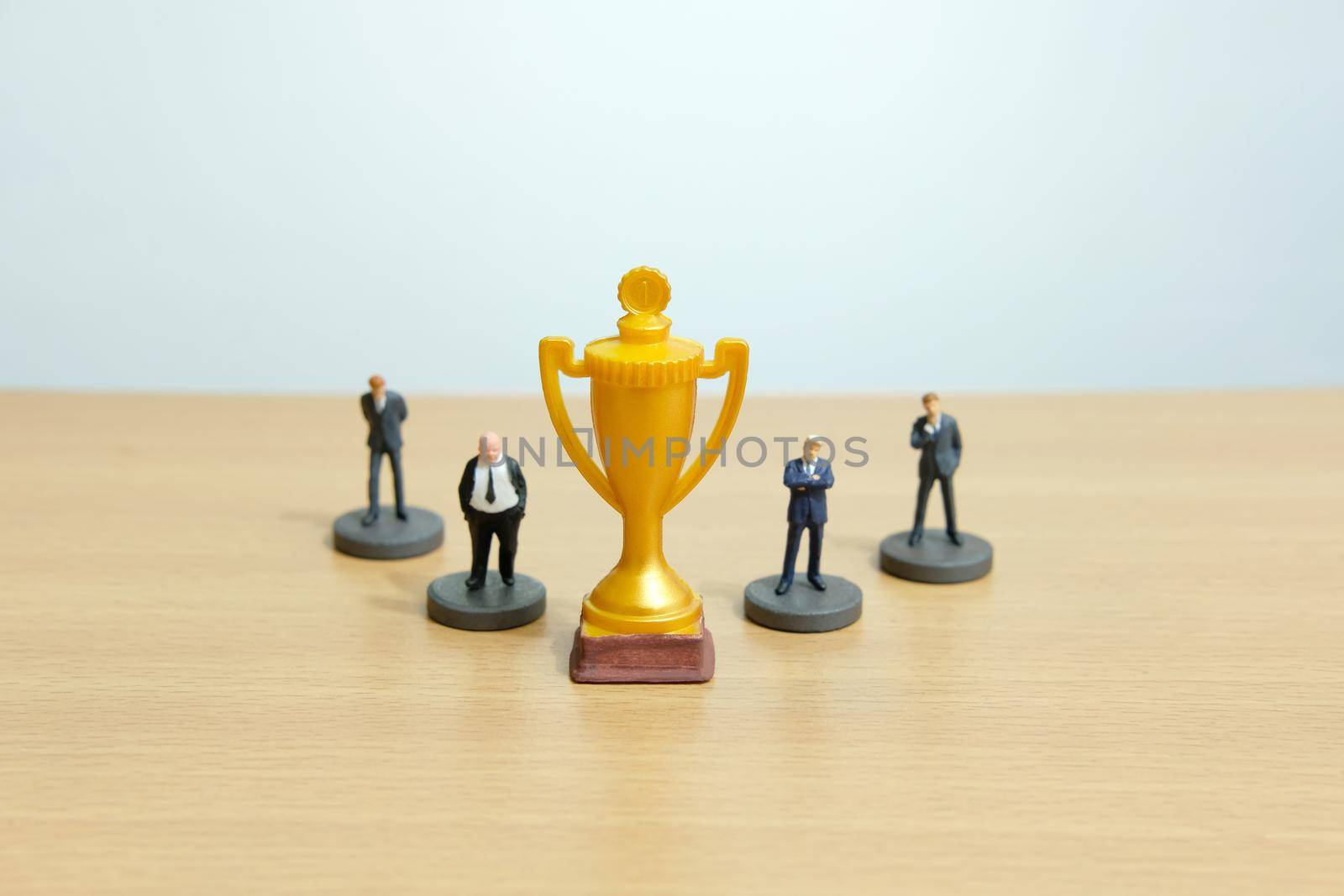 Miniature business concept - businessman lineup rank with golden trophy in the middle. Image photo