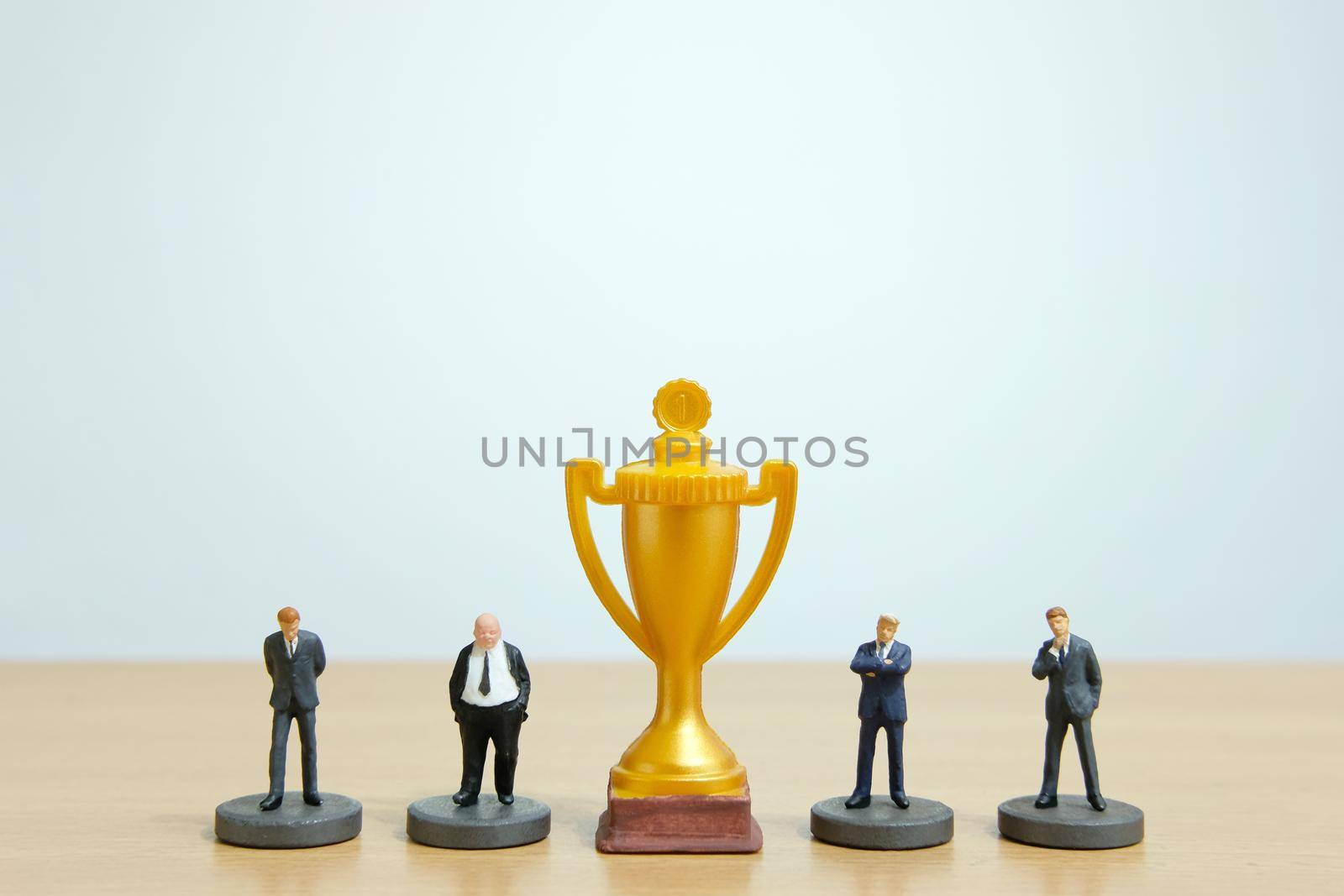 Miniature business concept - businessman lineup rank with golden trophy in the middle. Image photo