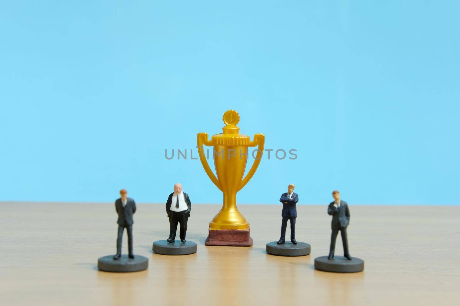 Miniature business concept - businessman lineup rank with golden trophy in the middle. Image photo