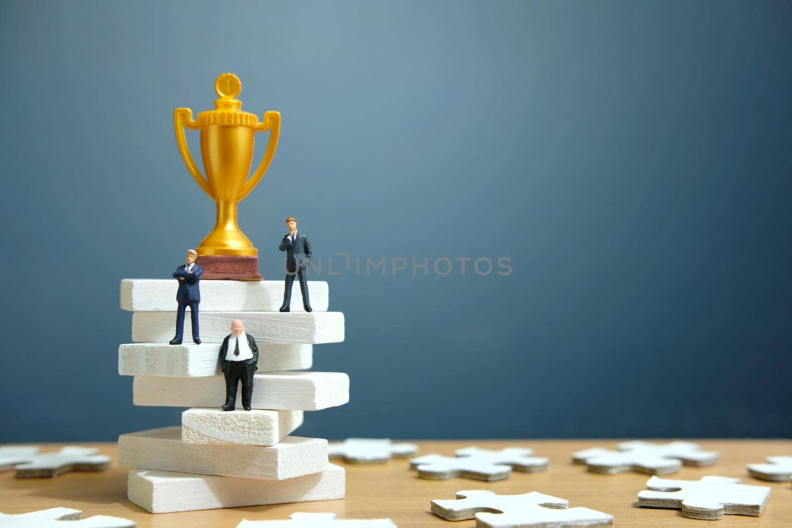 Miniature business concept - businessman standing on white staircase ladder with golden trophy above it. Image photo