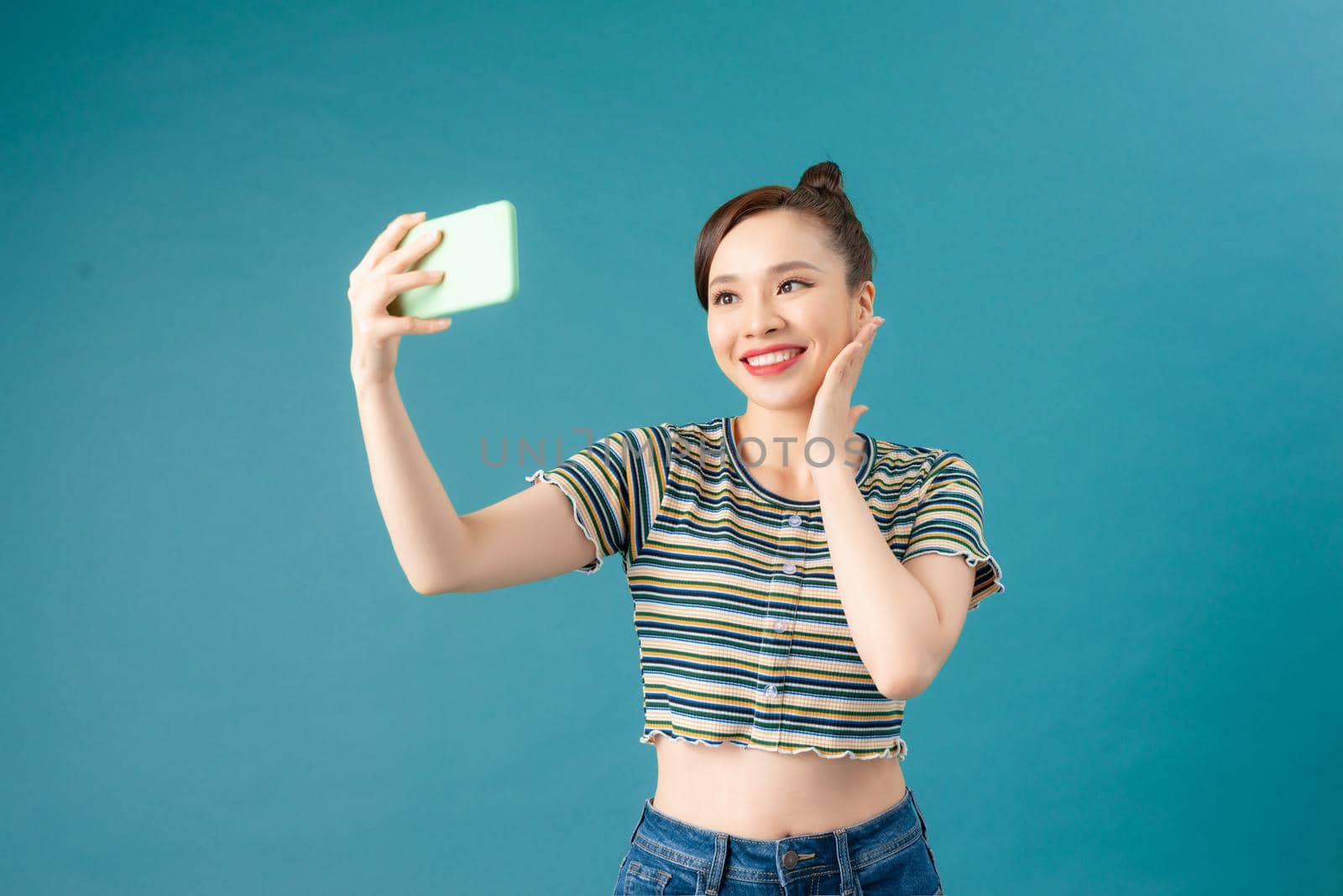 Smiling woman making selfie photo on smartphone over blue background