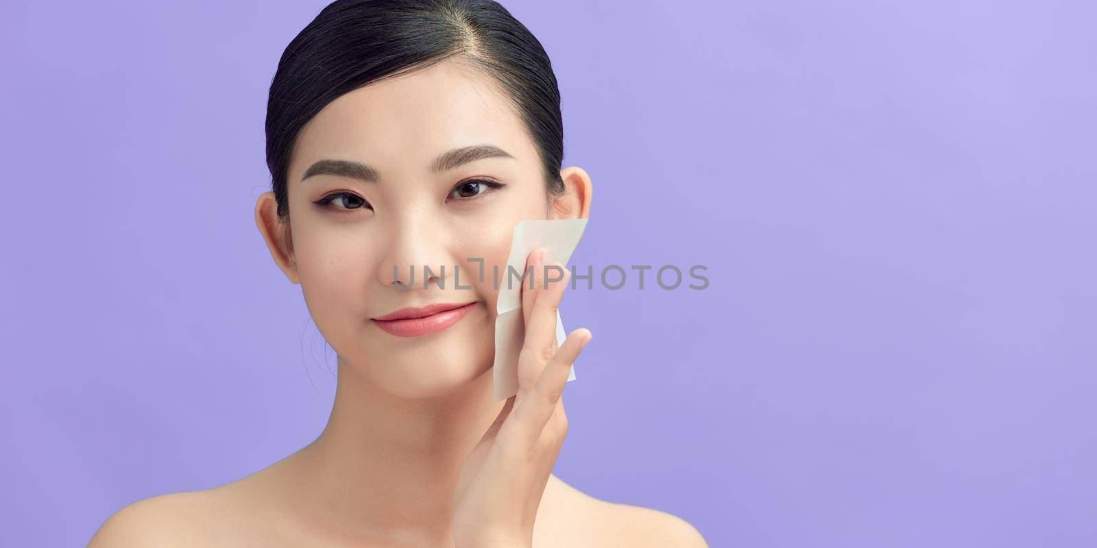 Women with oily skin using oil absorbing sheet on her face by makidotvn