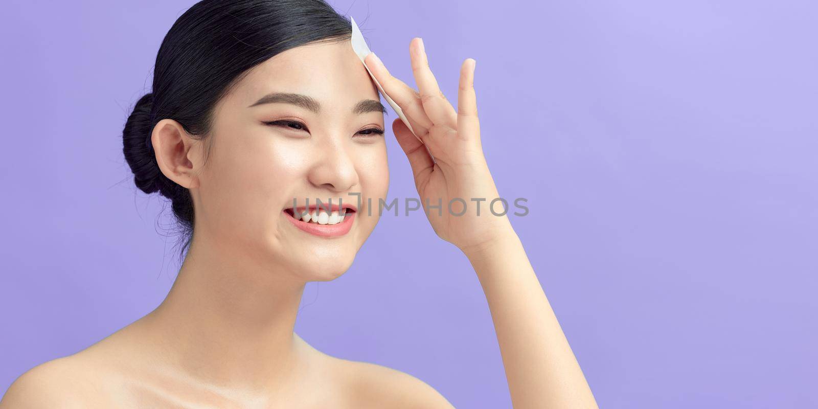 Women with oily skin using oil absorbing sheet on her face by makidotvn