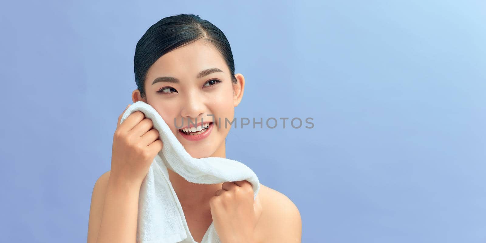 Young beautiful woman using a cotton towel to remove her makeup. by makidotvn