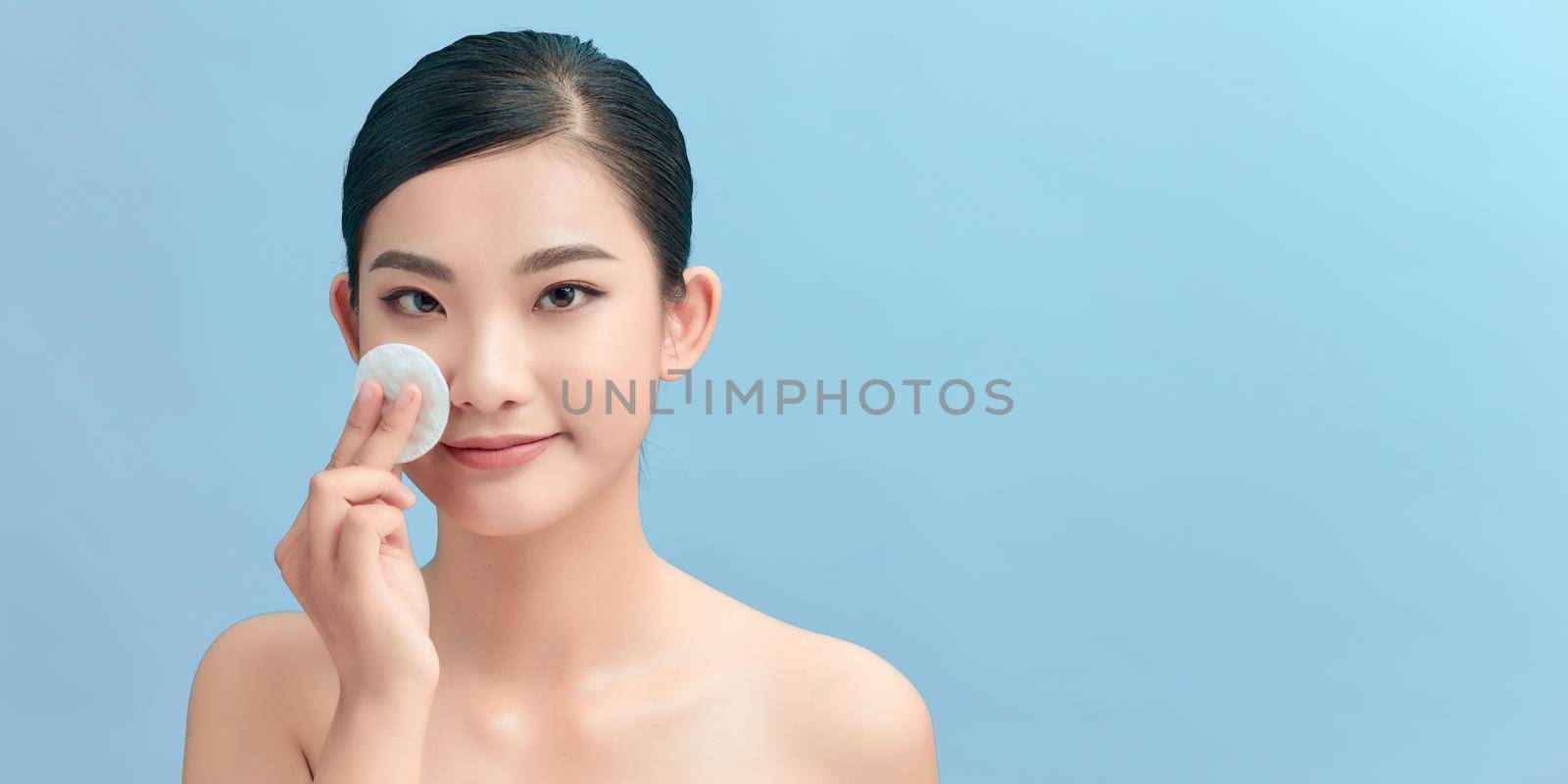 Asian woman cleaning beautiful face by wiping with cotton pad by makidotvn