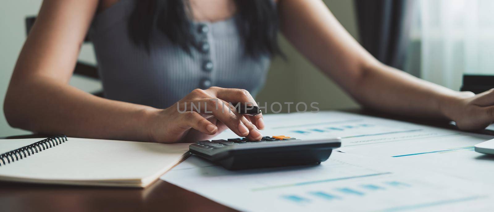 Business woman working in finance and accounting Analyze financial budget with calculator at home.