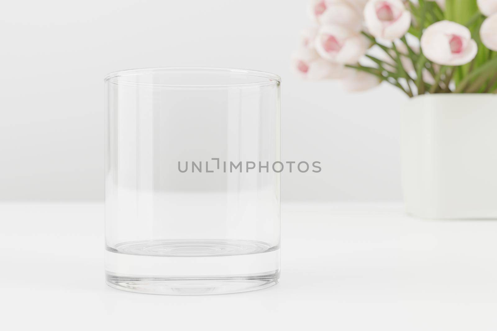 Empty water glass mockup on table with tulips and books.