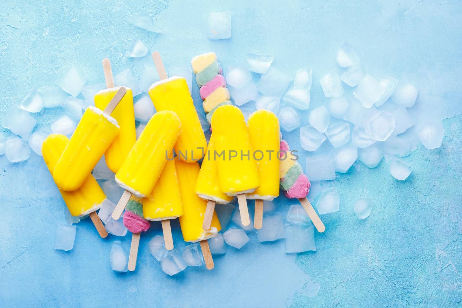 Exotic fruit ice cream sticks on blue background with ice cubes. Top view, blank space by Slast20