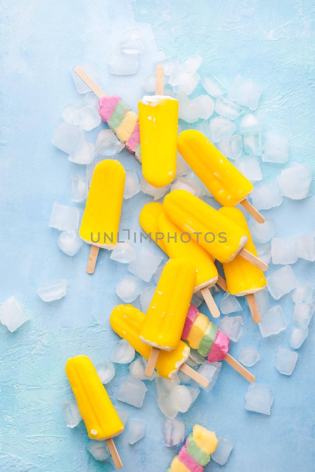 Ice cream sticks on blue background with ice cubes. Top view, blank space