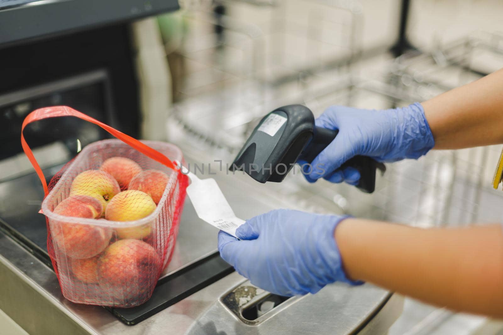 Scanning bar code. Woman or worker in blue medical gloves holding bar code scanner and scanning  paper on peach fruit. Shopping during the corona virus pandemic, selective focus by Slast20