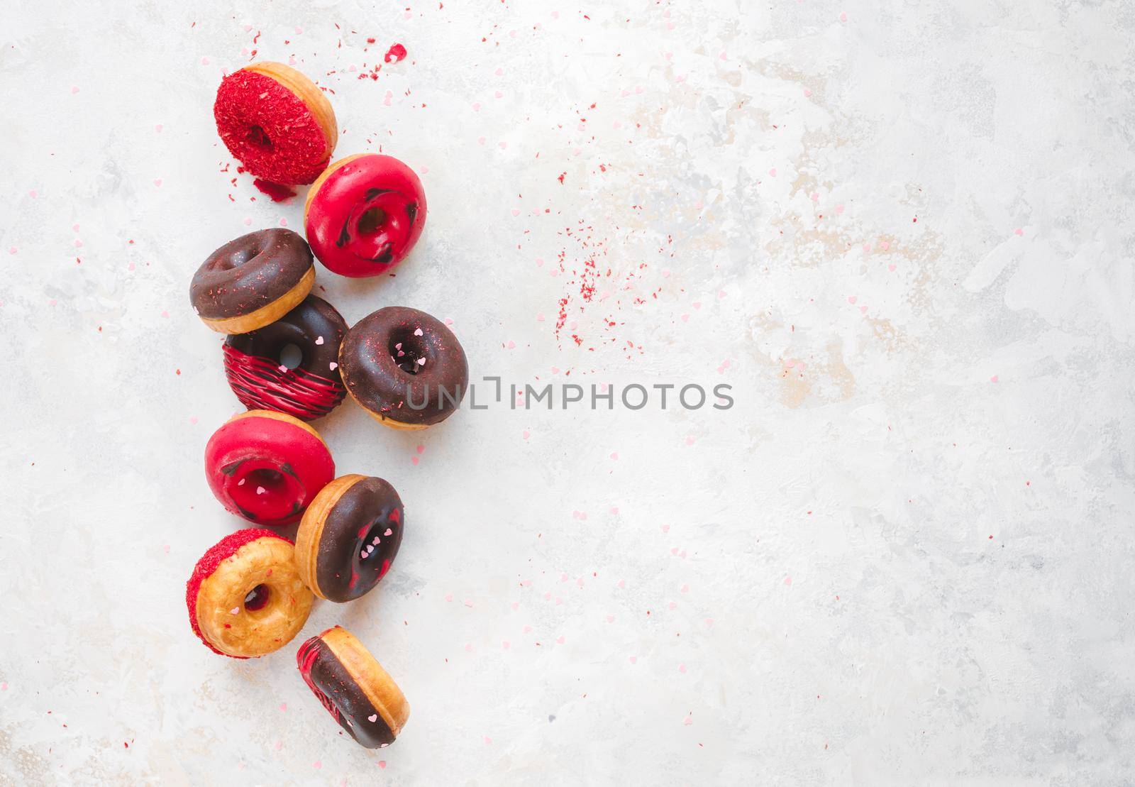 Mini chocolate doughnuts with icing and sugar sprinkles  on rustic white background. Top view, blank space