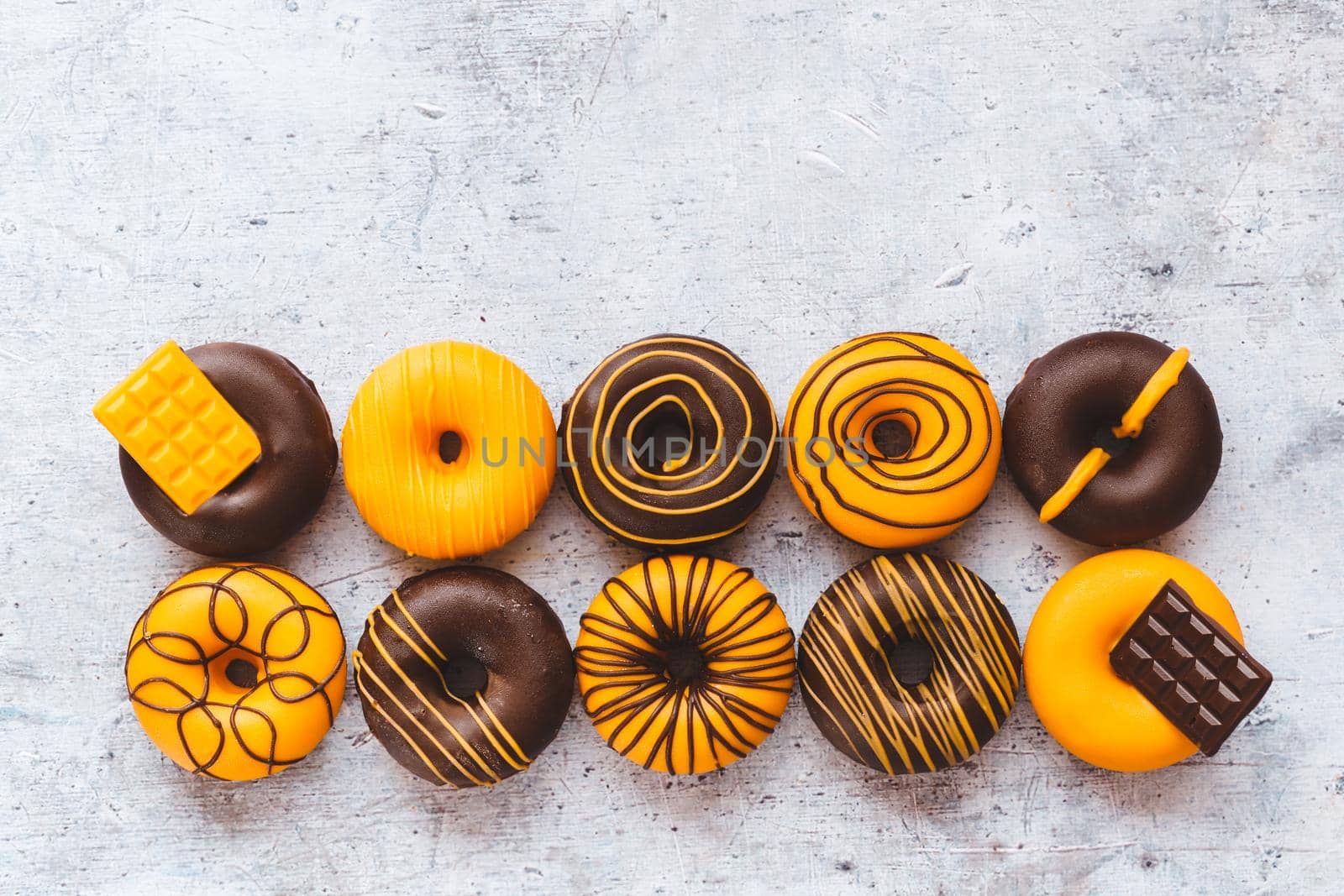 Homemade Orange  And Yellow Glazed Chocolate Donuts  On Rustic Gray Background. Top view, blank space by Slast20