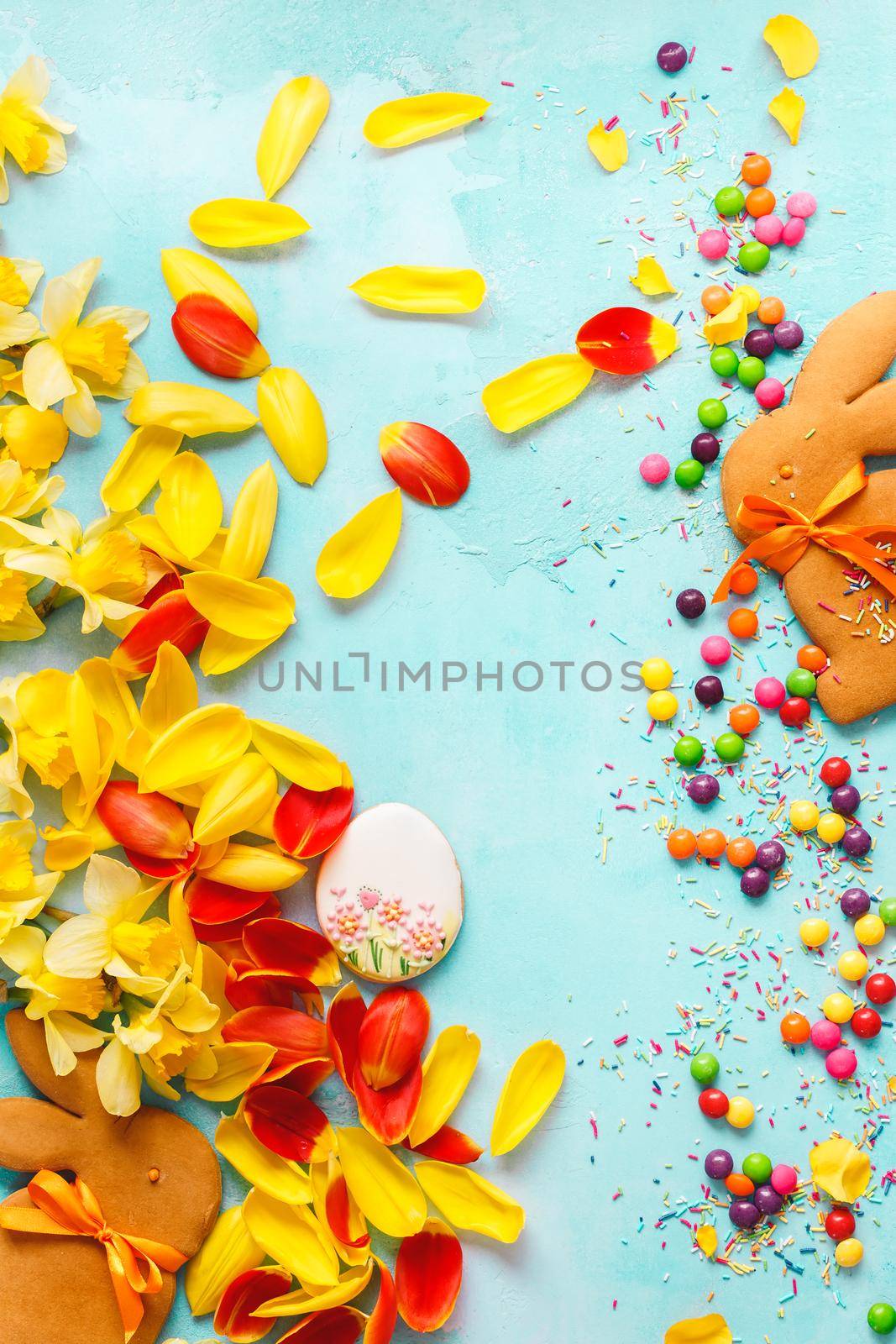 Happy Easter Background. Easter  bunny biscuits, egg sugar cookie, candy and yellow and red petal background. Top view, blank space