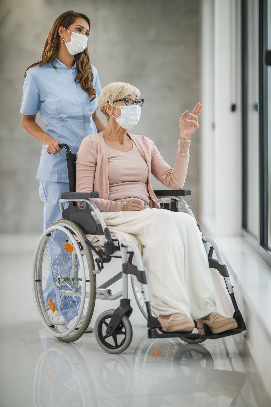 Shot of a young caregiver caring a senior female wheelchair-bound patient.