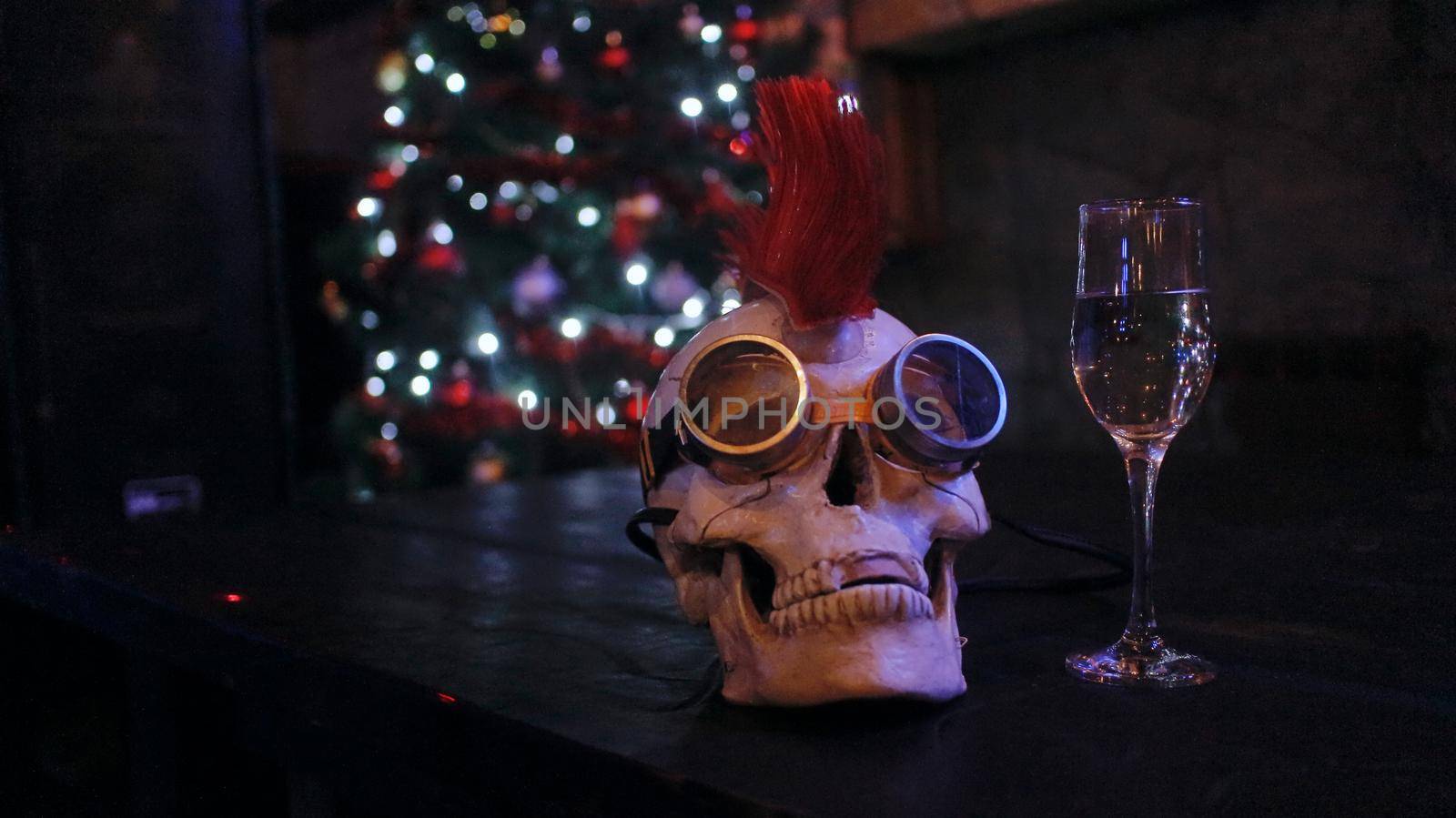 A glass of wine with a skull on the background of the Christmas tree