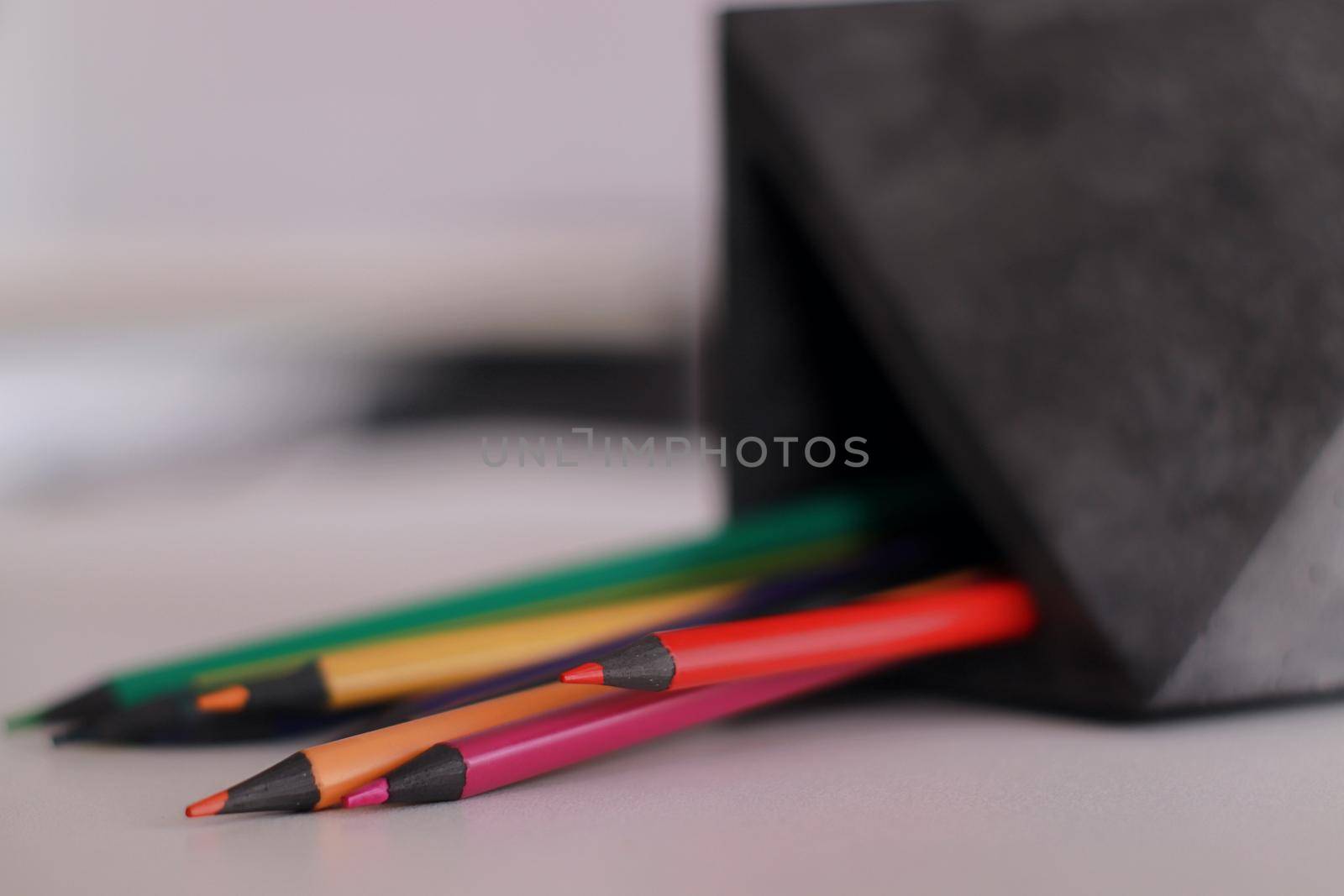 A close up of pencils in a concrete organizer. Colors. On a white table lying