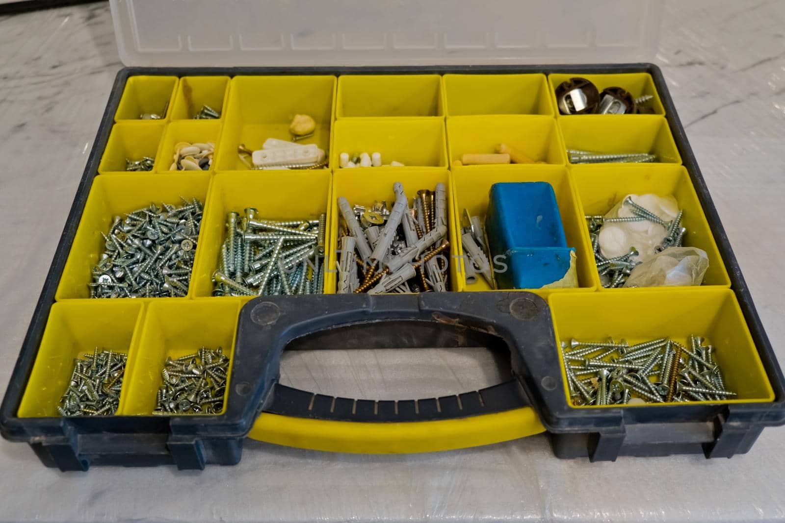 Small plastic yellow boxes with different screws and fasteners. Selective focus.