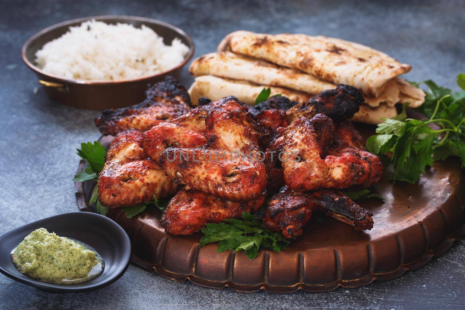 Spicy tandoori chicken wings served with mint chutney dipping sauce, pilau rice and garlic naan, selective focus by Slast20