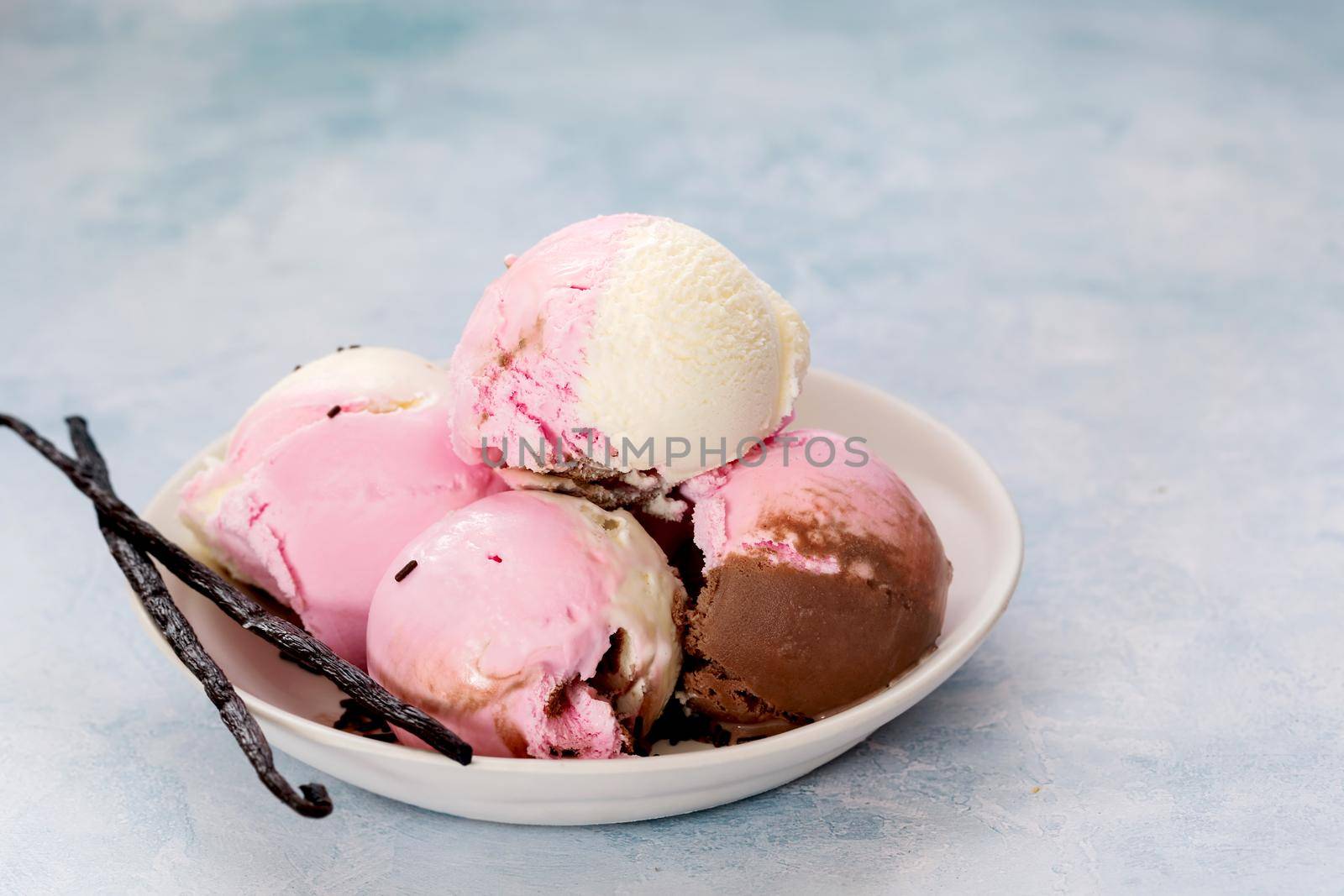 Bowl of Neapolitan ice cream scoops on rustic background. Selective focus, copy space by Slast20