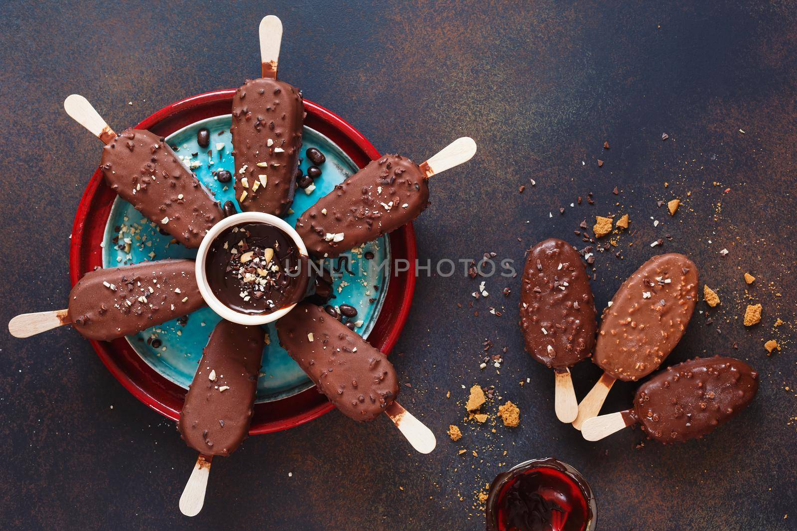 Chocolate covered ice cream sticks with milk and dark chocolate on rustic background. Top view, blank space