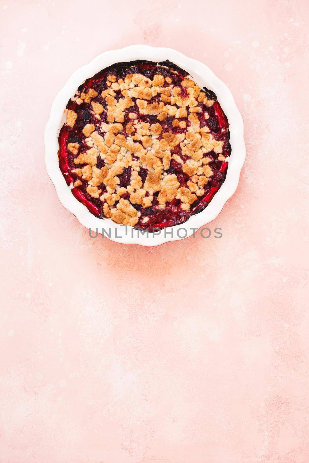 Mixed berry crumble in baking dish on rustic table. Top view, blank space