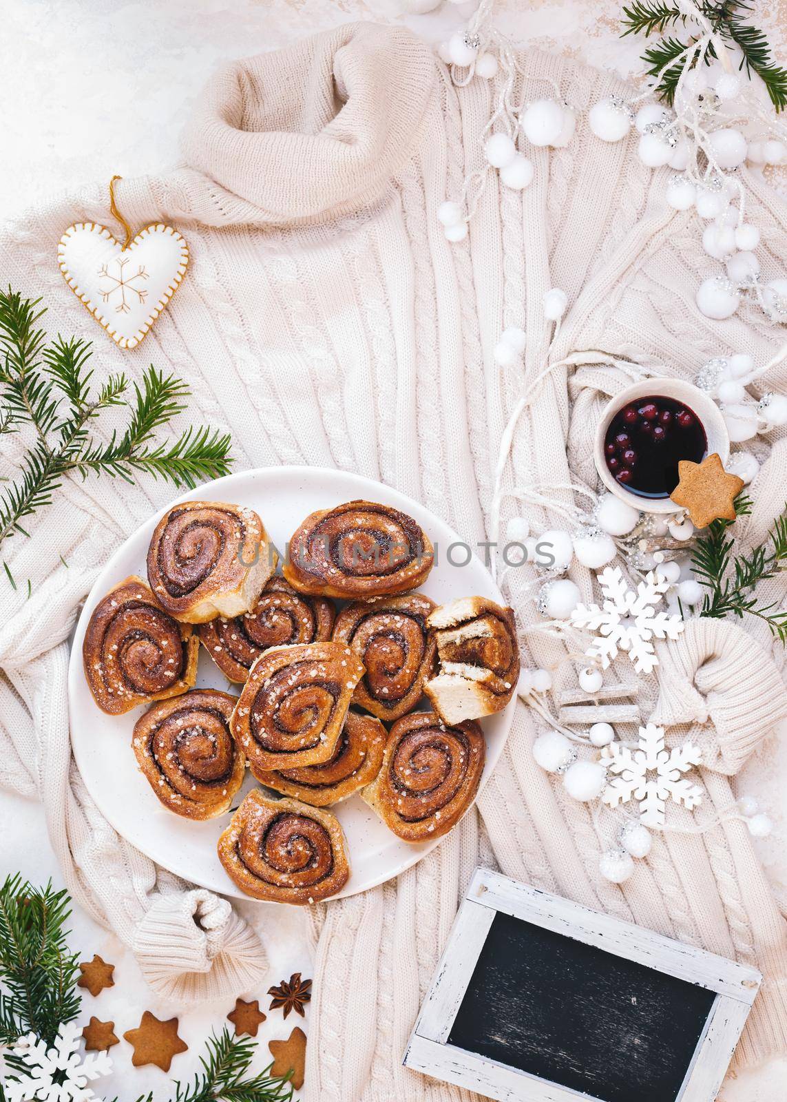 Cozy festive, Christmas, lifestyle concept. Freshly baked cinnamon rolls , knitted woolen light beige sweater and Christmas decorations . Top view,  copy space