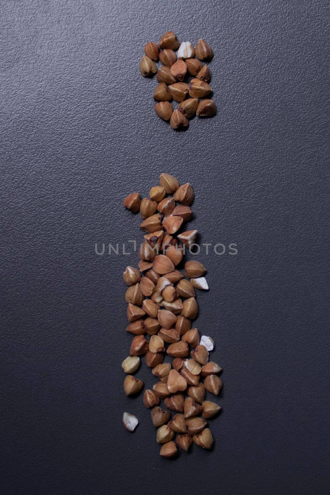 Letter 'i' written with buckwheat On gray background, top view, copy space. Food supplies crisis, food donation by oliavesna