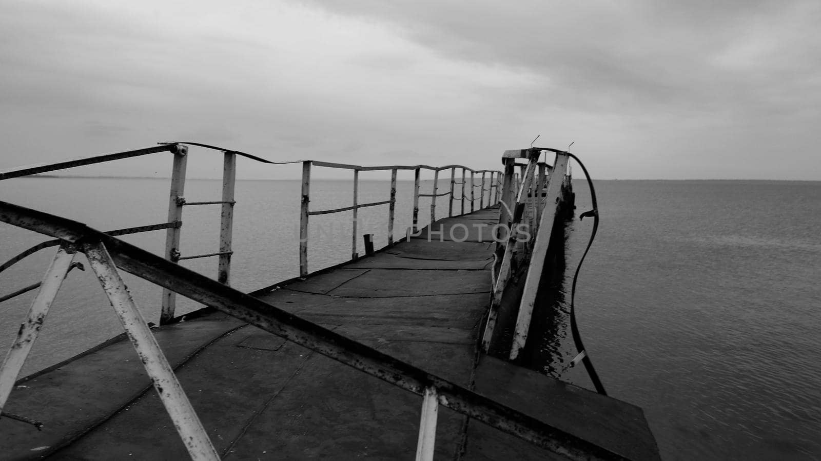 Black and white photo - broken old bridge in the sea - horizontal photo