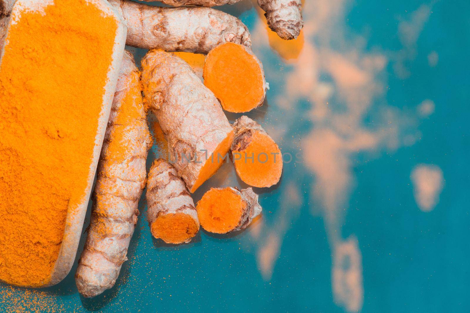 Turmeric powder (Kurkuma) in a wooden spoon and roots  by Weltblick